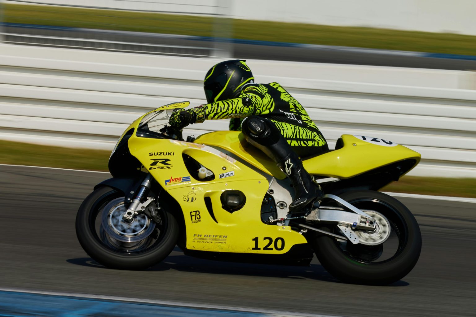 Professional motorcyclist racing at Hockenheimring on a bright day.